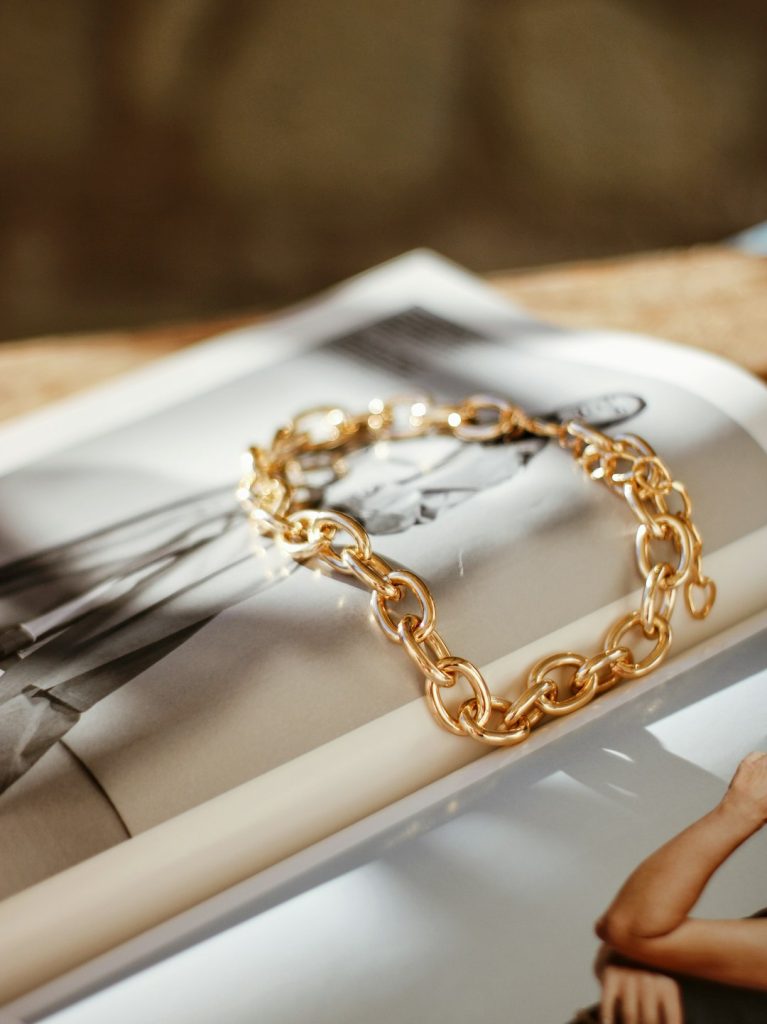 a gold chain bracelet sitting on top of a magazine oo0jaojhquk.jpeg